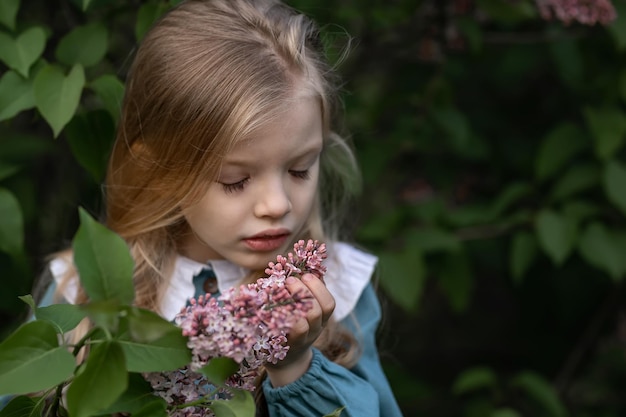 La bambina in giardino annusa il fiore lilla