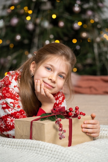 La bambina in pigiama la mattina presto ha trovato un regalo di Babbo Natale sotto l'albero