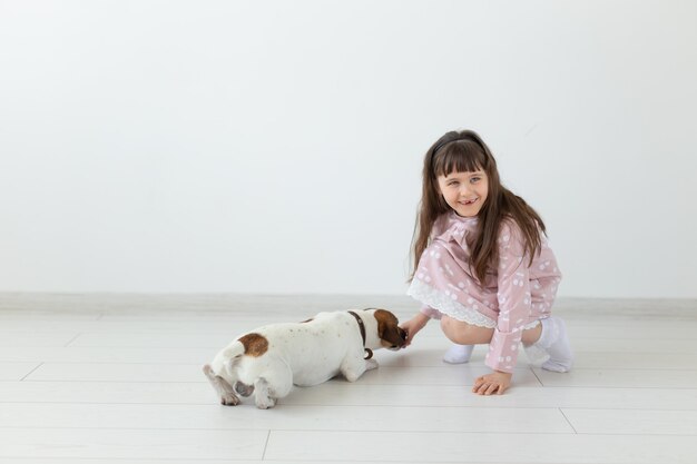 La bambina in un vestito rosa gioca con il suo cane Jack Russell Terrier