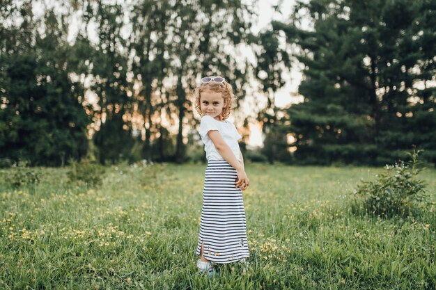 La bambina in vestito mostra all'aperto