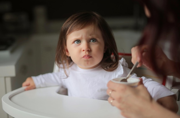 La bambina mangia sul seggiolone allattato da sua madre