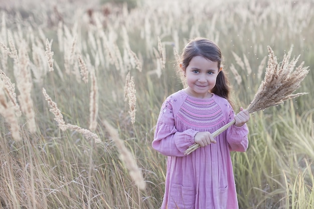 la bambina nel campo tiene un mazzo di grano.