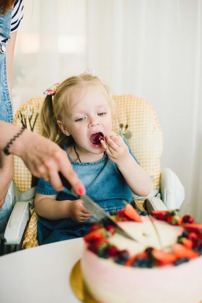 La bambina per il suo compleanno accetta le congratulazioni e mangia la torta