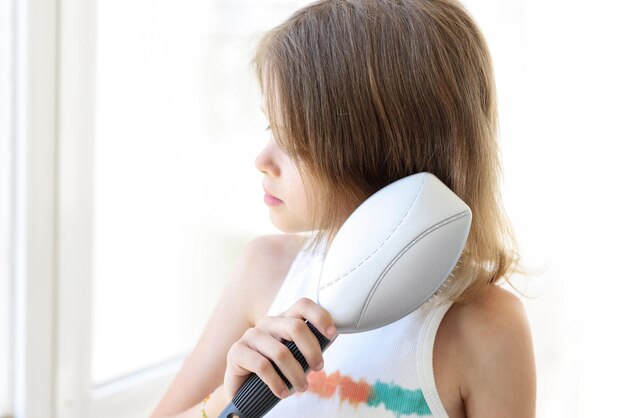 La bambina pettina i capelli con il concetto di cura dei capelli del bambino del pettine