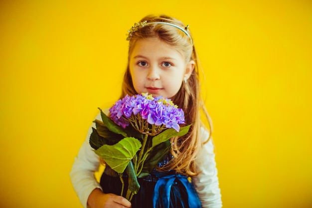 La bambina pone con violetta viola prima della parete gialla