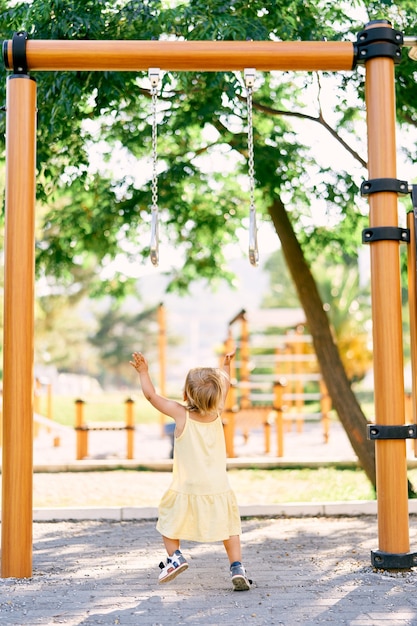 La bambina raggiunge la barra orizzontale nella vista posteriore del parco giochi