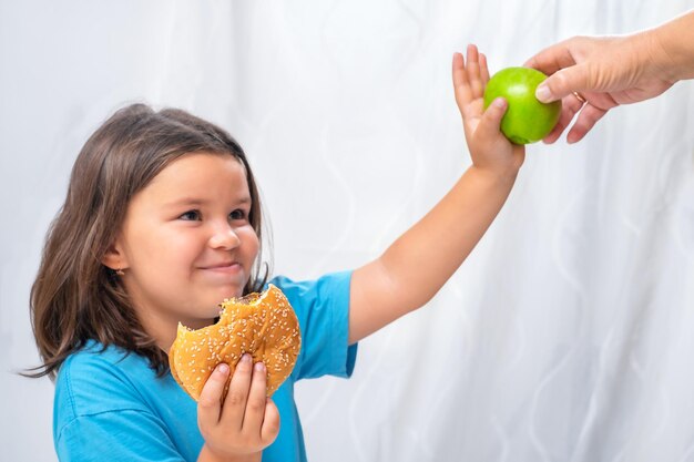 La bambina rifiuta una mela dalle mani di un anziano e sceglie un hamburger