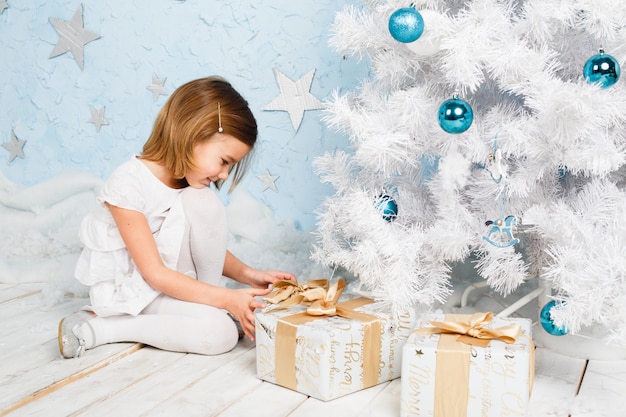 La bambina scioglie il nastro su un regalo di Natale