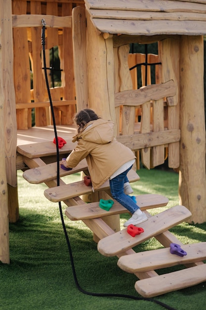 La bambina si arrampica su per la collina nel parco giochi con molta energia