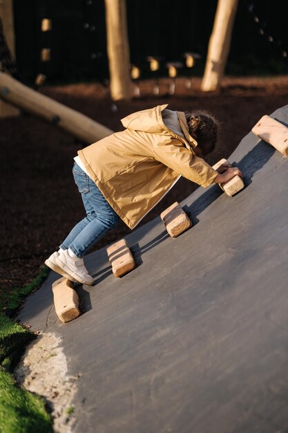 La bambina si arrampica su per la collina nel parco giochi con molta energia