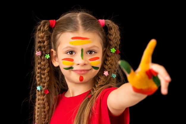 La bambina si è macchiata di vernice le mani e il viso.