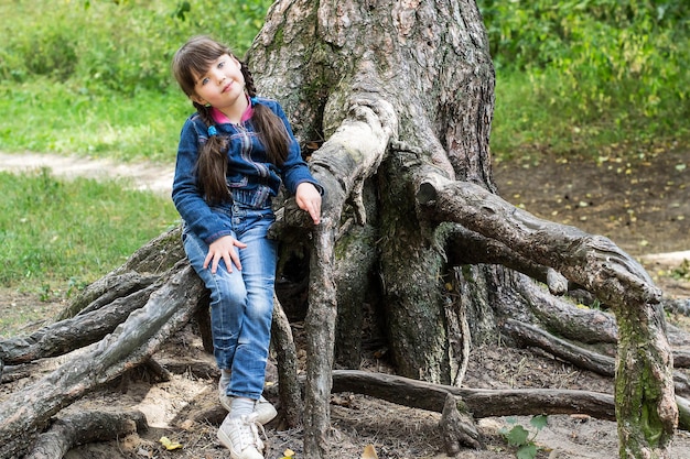 La bambina si sedette per riposare sulle radici di un albero