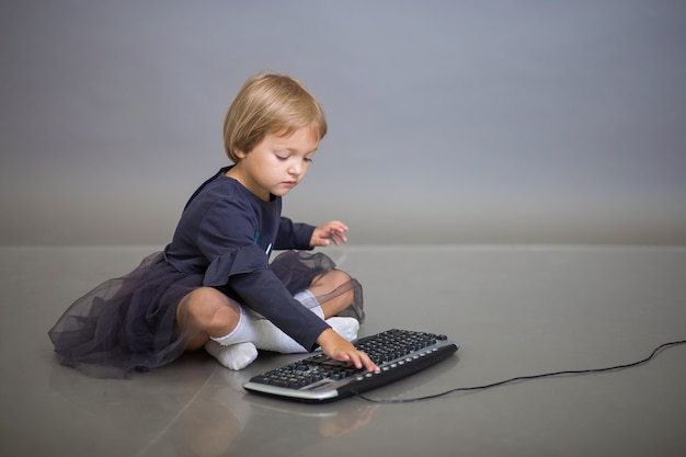 La bambina si siede e gioca con la tastiera