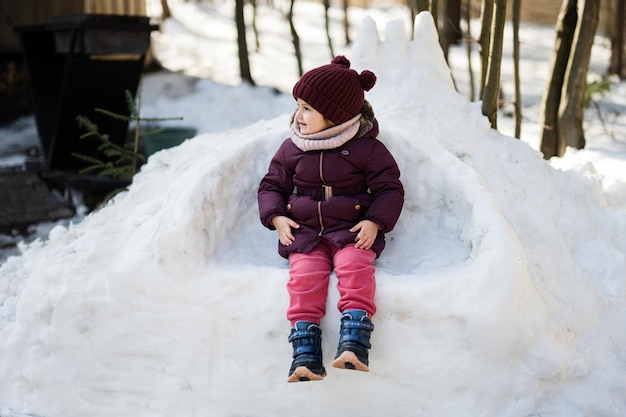 La bambina si siede su un trono improvvisato fatto di neve