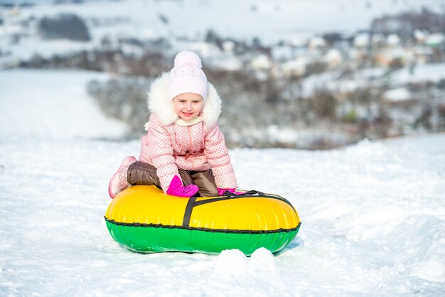 La bambina si siede sul tubo di neve