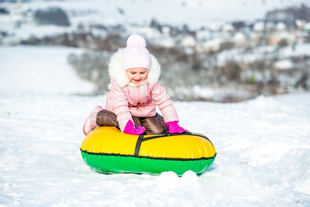 La bambina si siede sul tubo di neve