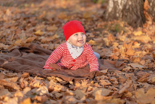 La bambina sorride allegramente sdraiata su un morbido tappetino in una calda giornata autunnale nel parco