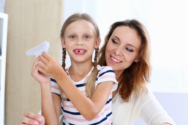 La bambina sorridente bionda fa l'aereo di carta