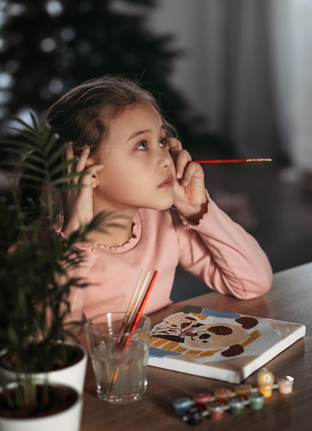 La bambina sta dipingendo con la tempera. Bambina felice che dipinge a casa. La ragazza disegna un'immagine con i numeri.