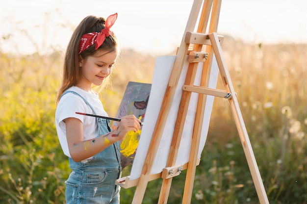 La bambina sta dipingendo l'immagine all'aperto