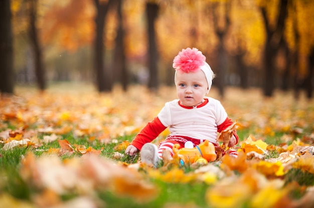 La bambina sta giocando nel parco d'autunno con un sorriso.