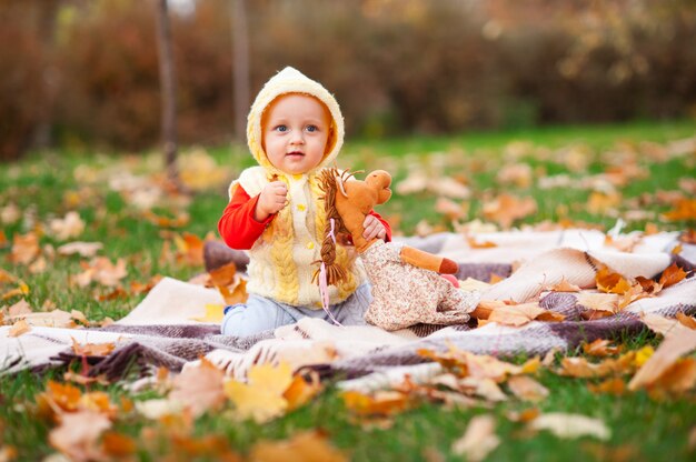 La bambina sta giocando nel parco d'autunno con un sorriso.