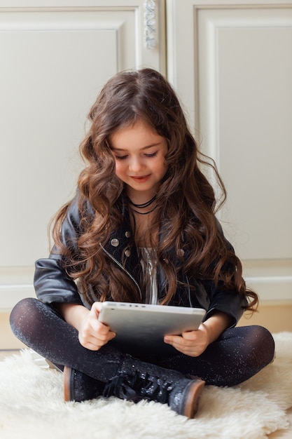 La bambina sta giocando utilizzando il tablet mentre era seduto sul pavimento nella sua stanza