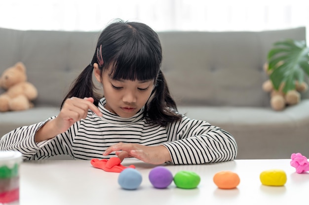 La bambina sta imparando a usare la pasta da gioco colorata in una stanza ben illuminata