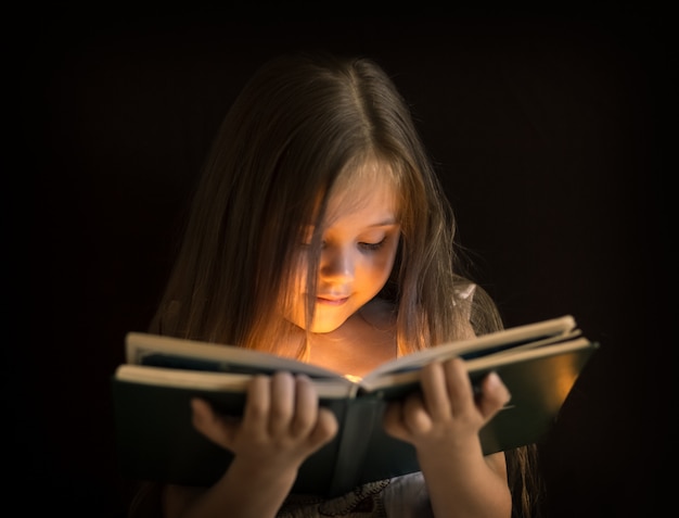 La bambina sta leggendo un libro magico