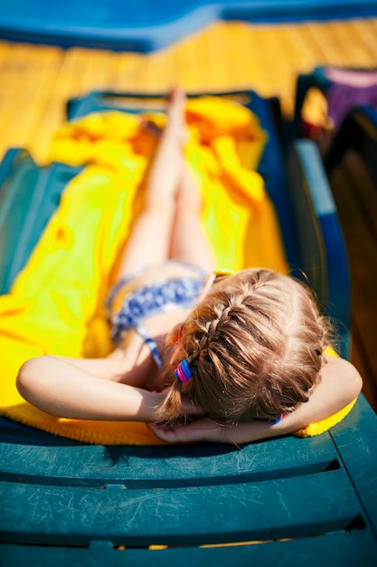 La bambina sta prendendo il sole su un lettino vicino alla piscina del resort