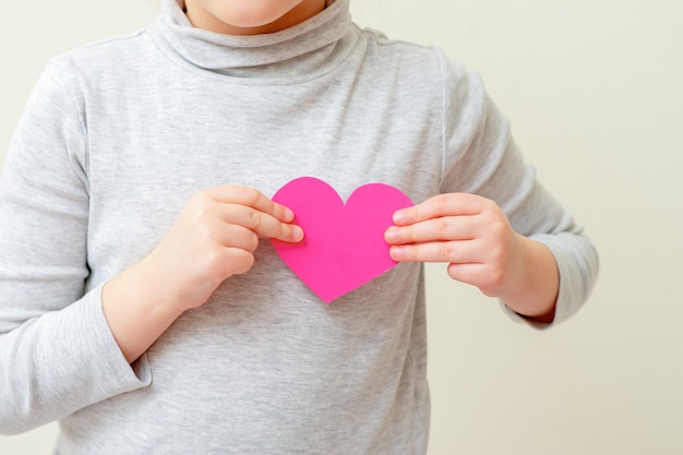 La bambina sta tenendo il cuore rosa.