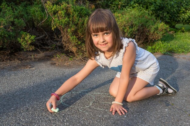 La bambina sull'asfalto disegna con il gesso
