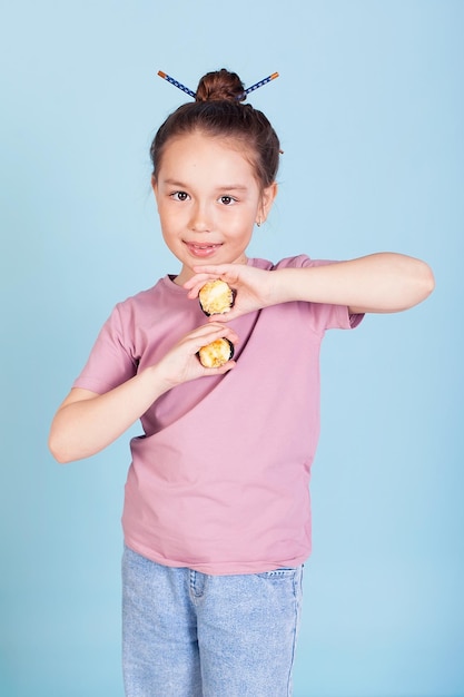 La bambina sveglia ama mangiare il sushi Ragazza prescolare divertente divertente con un rotolo di sushi e su sfondo blu