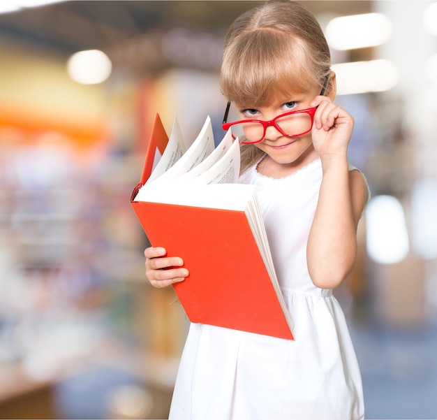 La bambina sveglia con gli occhiali legge il grande libro