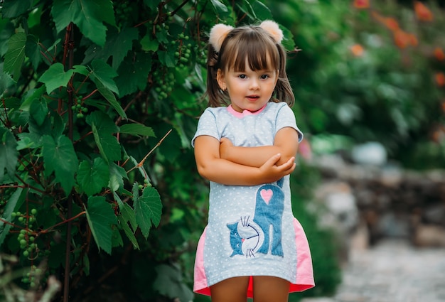 La bambina sveglia con le mani piegate sta vicino all'uva verde.