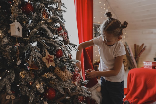 La bambina sveglia decora un albero di Natale. Buon Natale e vacanze di Capodanno.