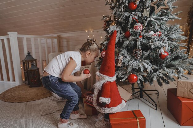 La bambina sveglia decora un albero di Natale. Buon Natale e vacanze di Capodanno.