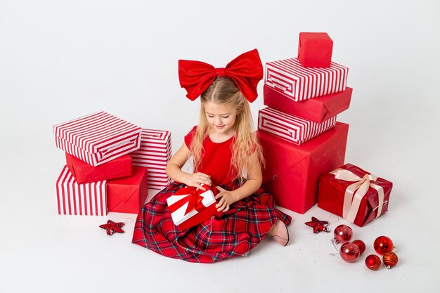 La bambina sveglia è considerata per Natale. sfondo bianco, grandi scatole regalo, spazio per il testo. Il concetto di Natale