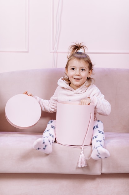 La bambina sveglia è sdraiata sul divano rosa