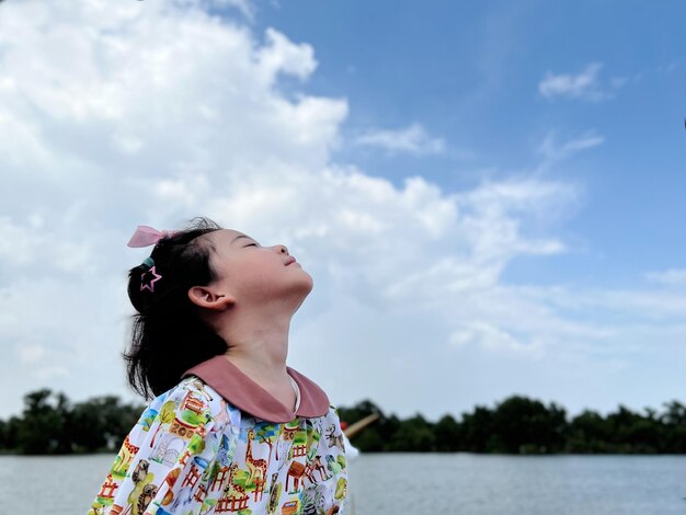 La bambina sveglia esamina il cielo luminoso del giorno per nuove opportunità