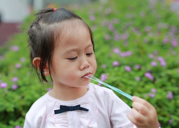 La bambina sveglia gode di di mangiare la gomma da masticare