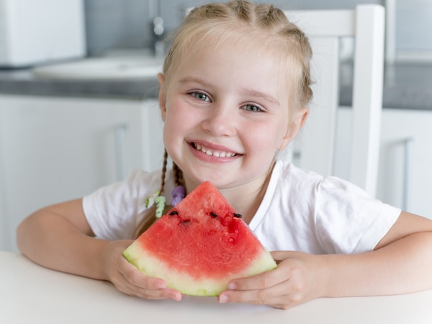 La bambina sveglia mangia un'anguria nella cucina