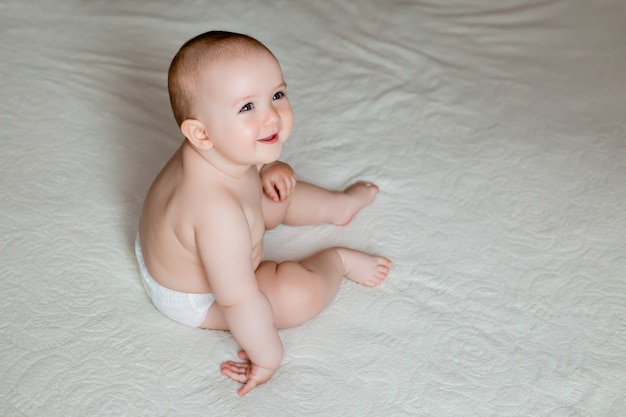 La bambina sveglia si siede sul letto della casa nella stanza, spazio per il testo