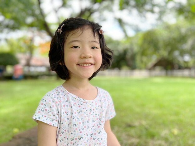 La bambina sveglia sorride nel giardino con lo spazio della copia