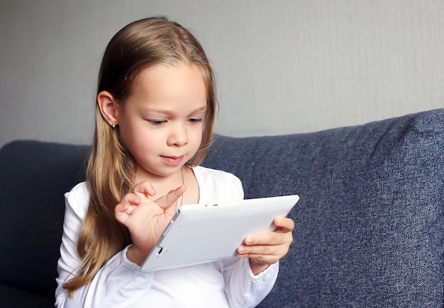 La bambina tiene il tablet tra le mani e lo guarda.