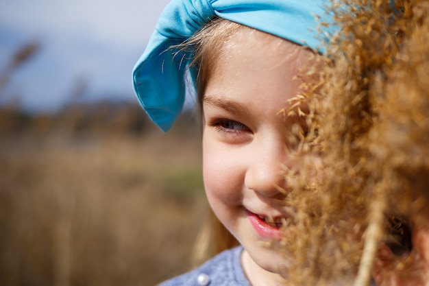 La bambina tiene in mano canne secche, tempo primaverile soleggiato, sorrisi e gioia del bambino