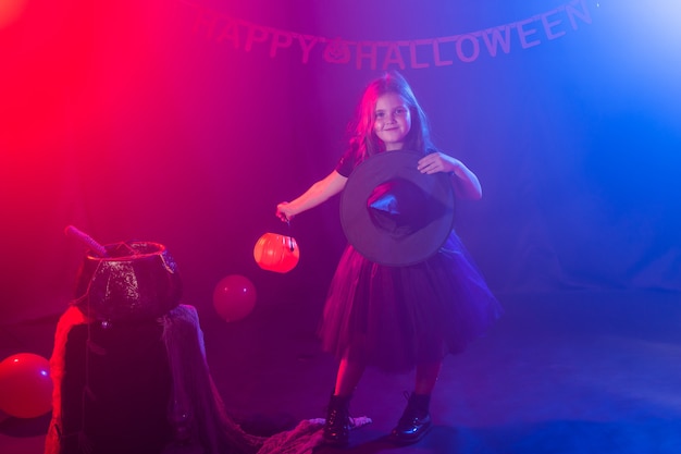 La bambina tiene la presa della zucca durante le vacanze di halloween, la bambina indossa il costume da strega fantasia fiaba