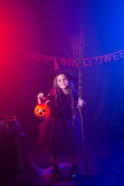 La bambina tiene la scopa durante le vacanze di halloween, la bambina indossa un costume da strega fantasia fiaba e