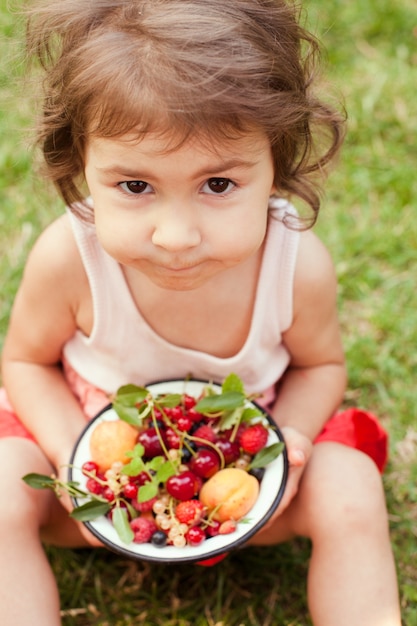 La bambina tiene una ciotola con frutta estiva