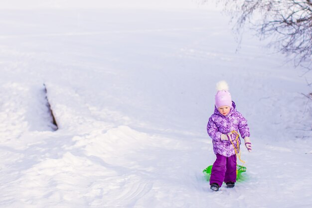 La bambina tira una slitta in una calda giornata invernale